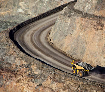 A yellow truck drives up a winding road on a mine site
