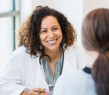 A female doctor in a white coat speaks to her patient