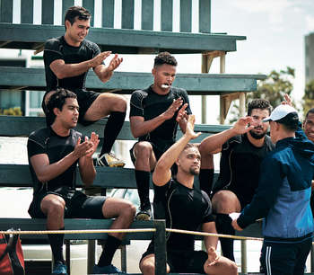 A group of male athletes sit on some bleachers