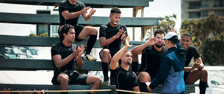 A group of male athletes sit on some bleachers