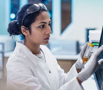 A woman in a lab coat reads data on a computer screen