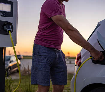 A man plugs a charger into an electric car