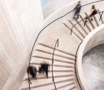 People walk down a curved staircase