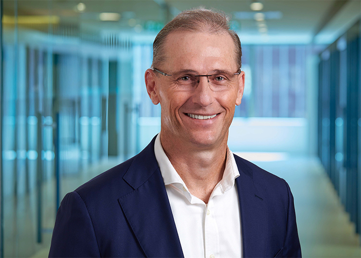 A photo of Darren Black looking straight ahead and smiling with a view of BDO Brisbane in the background