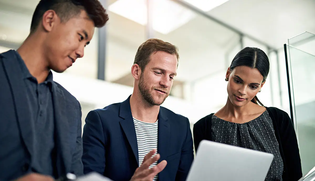Three professionals discussing work over a laptop.