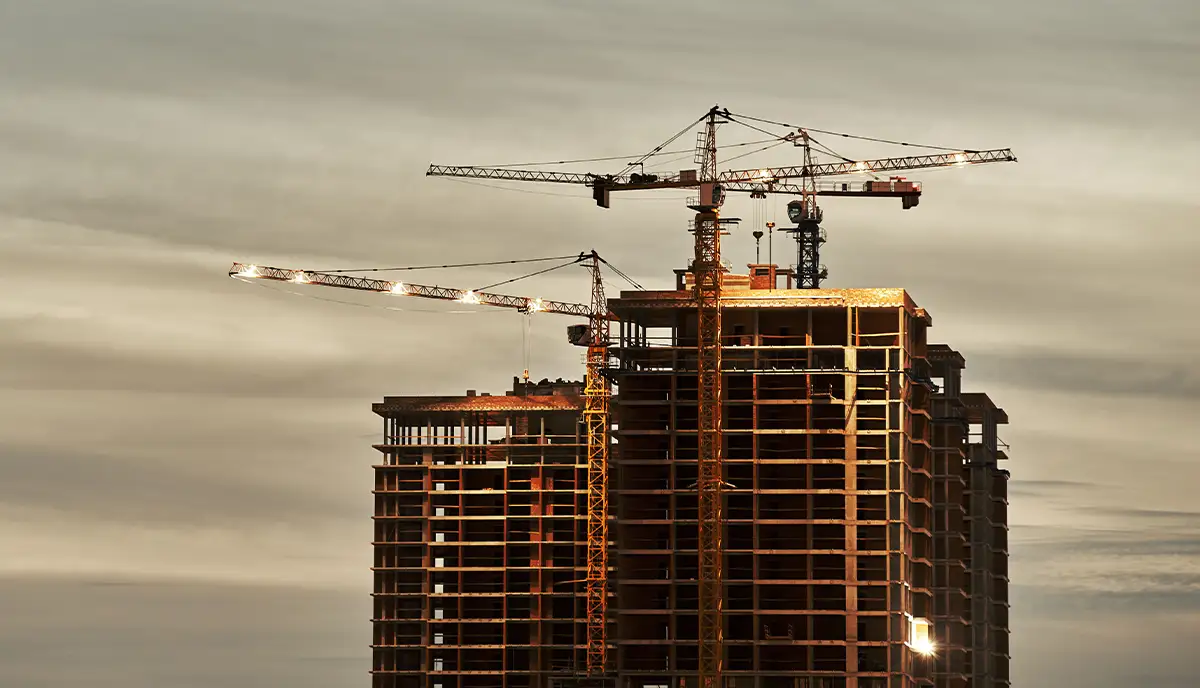 Building under construction with cranes and scaffolding.