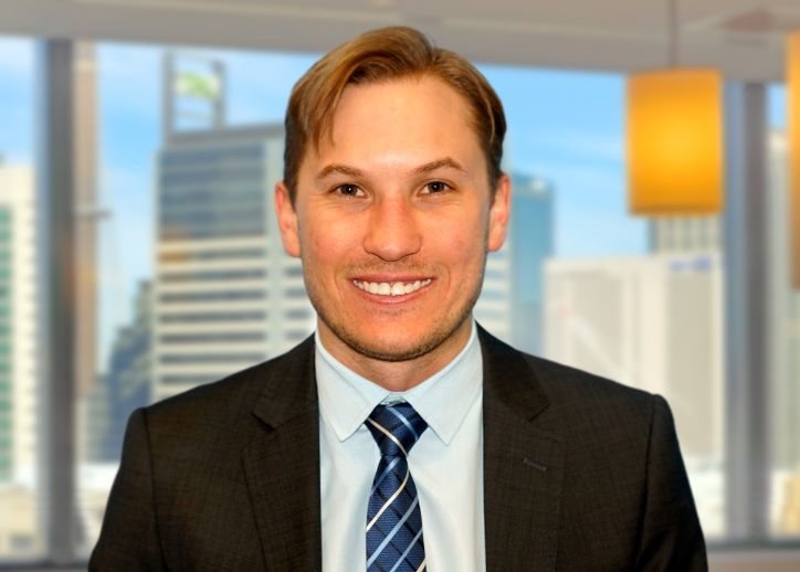 A photo of Brett Monk looking straight ahead with a view of Sydney in the background