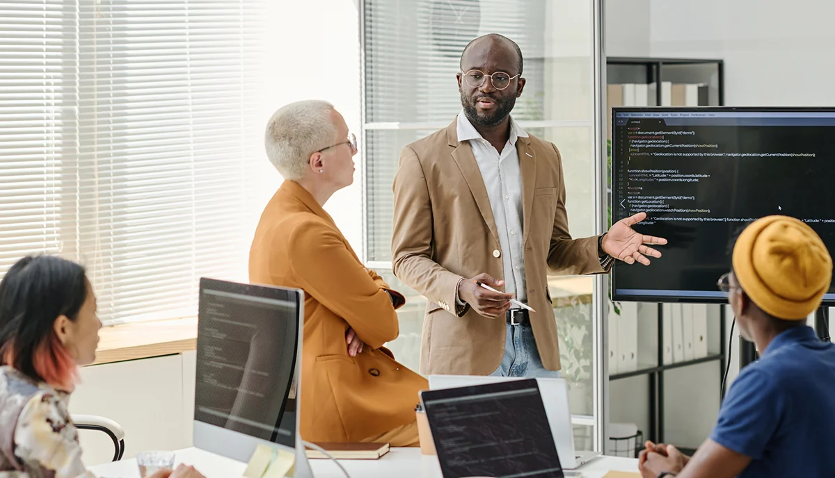 Businesspeople in a meeting looking at a screen, discussing what they need as a company.