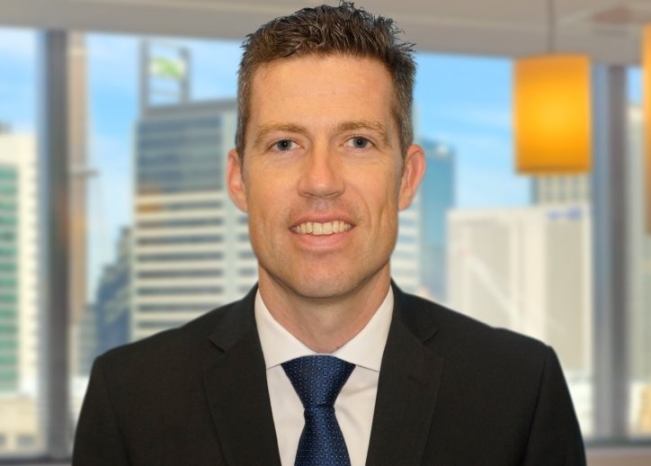 A photo of Gunnar Kaebisch looking straight ahead with a view of Sydney in the background