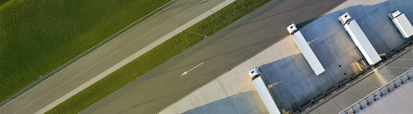 Aerial view of a logistics hub with four trucks at loading docks.