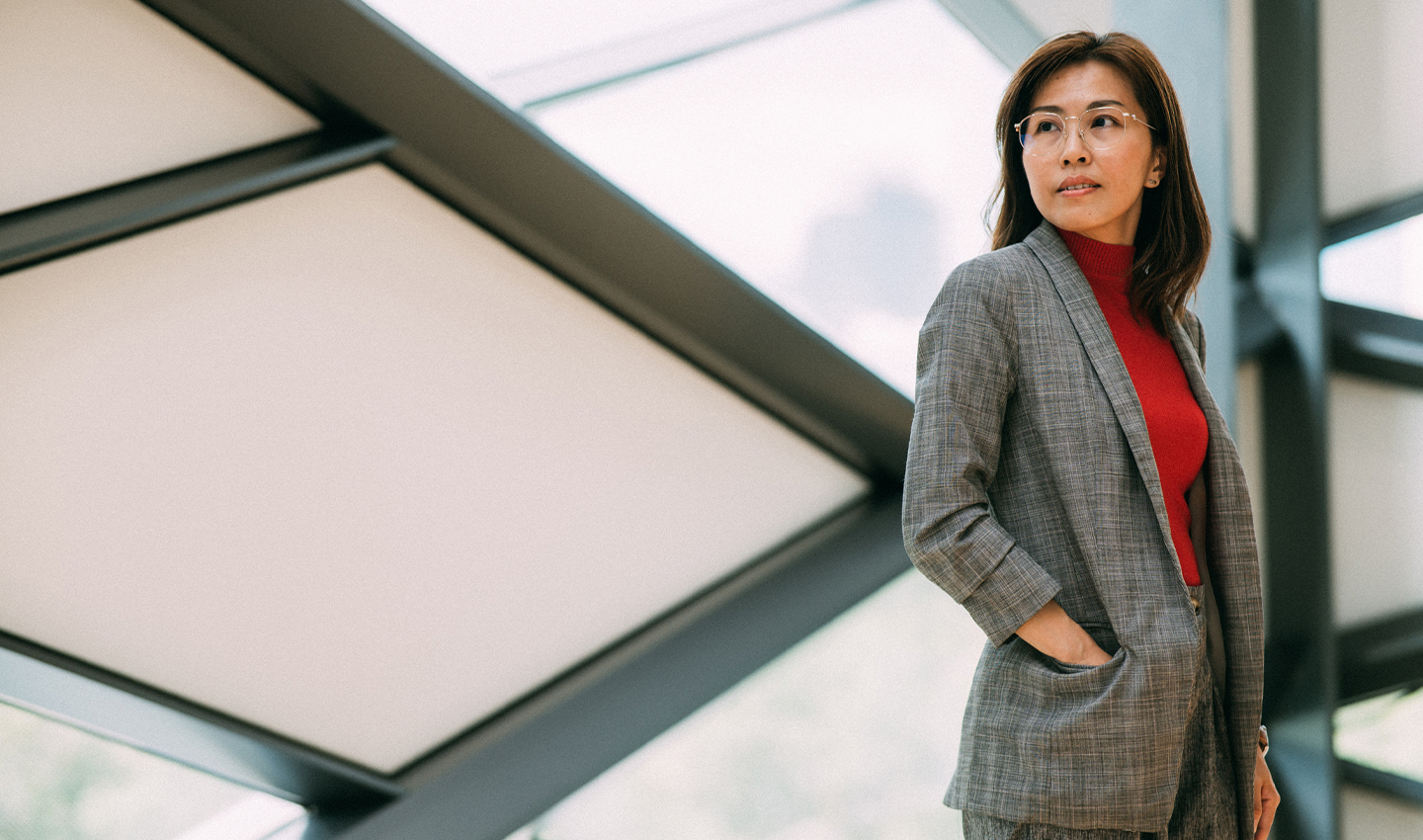 Person looking out into distance wearing a grey jacket and red tshirt.