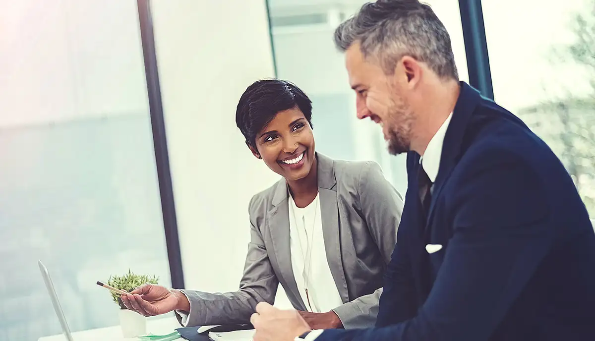 A man and woman sit talking and smiling.