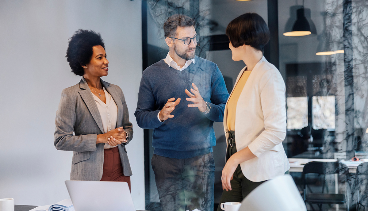 Three people talking in a meeting room, two female and one male. 