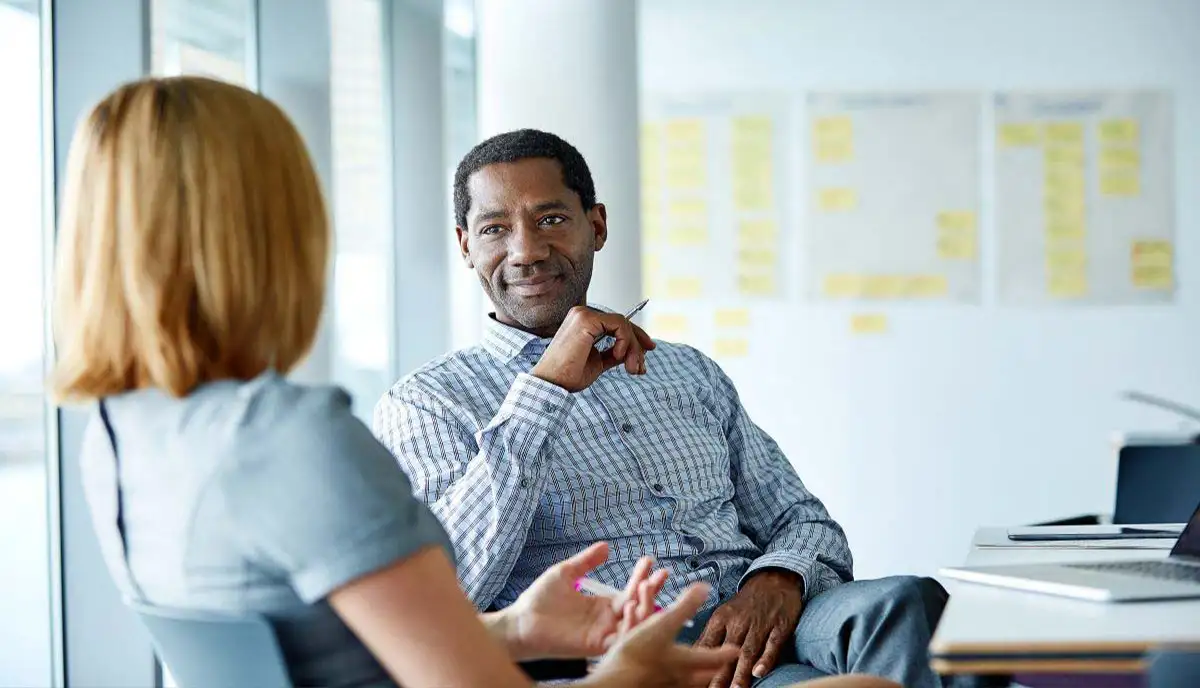 A man and woman sit talking and smiling.
