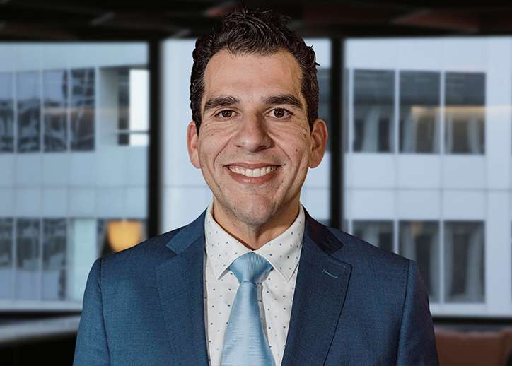 A photo of Ali Bolbol looking straight ahead with a view of Sydney in the background